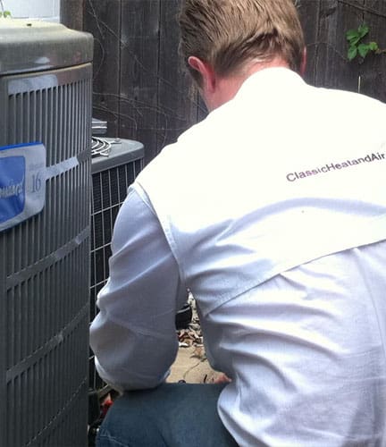 Classic Heating & Air employee looking at air conditioning unit