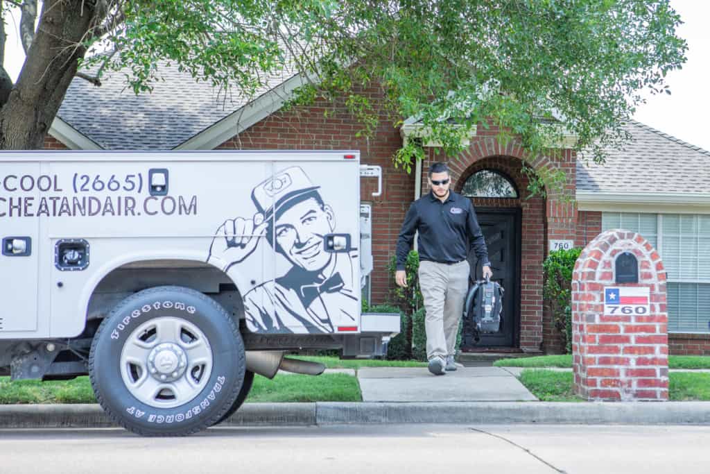 Man stepping out of the house carrying a machine and heading to the parked white classic heat and air van